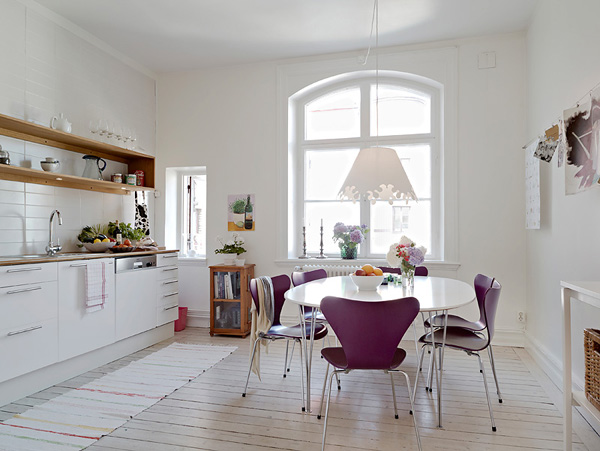 Biała kuchnia z jadalnią z nowoczesnymi i  fioletowymi krzesłami