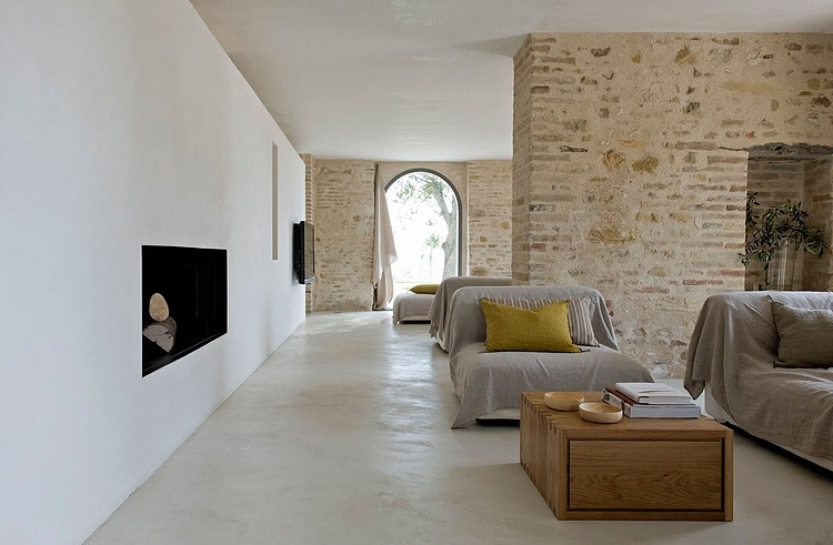 Otwaty salon z kamiennymi ścianami i nowoczesnym kominkiem wbudowanym w białą ścianę