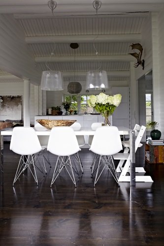 Szklane lampy wiszące nad nowoczesnym białym stołem z krzesłami Vitra na metalowych krzyżakach
