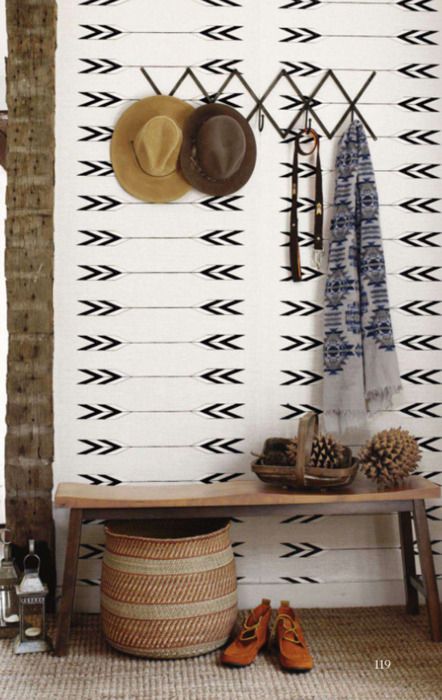 Drewniana prosta ławka z surowego drewna,biało-czarna tapeta z graficznym wzorem,dywan z juty,pleciony kosz,metalowy wieszak na ścianie w przedpokoju