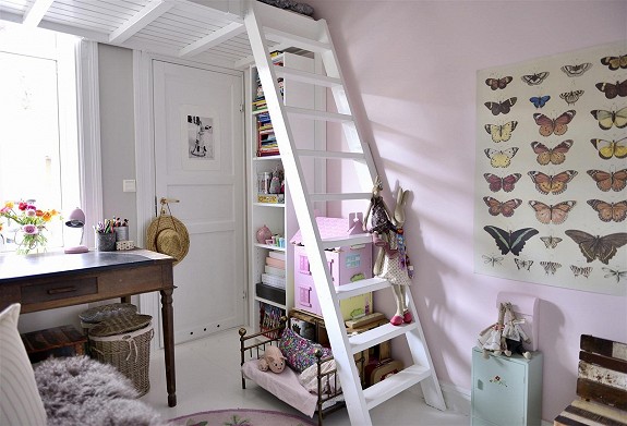 Białe schodki z półkami na antresolę z łóżkiem, stylowe biurko i plakat z motylami w dziecięcym pokoju