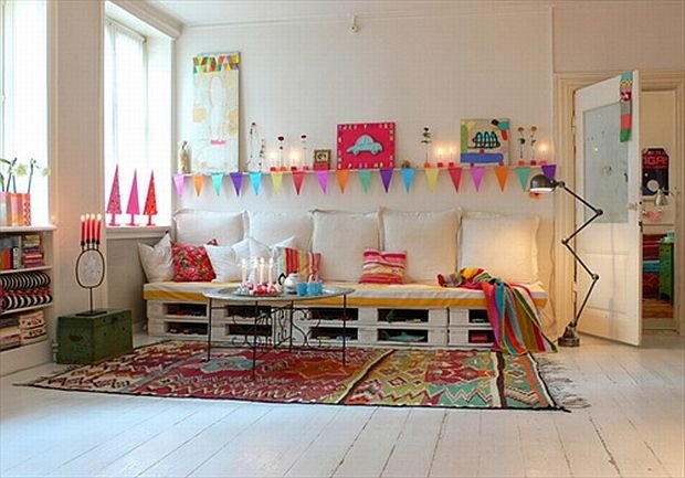 Kolorowy skandynawski salon z siedziskami knapą z drewnianych palet