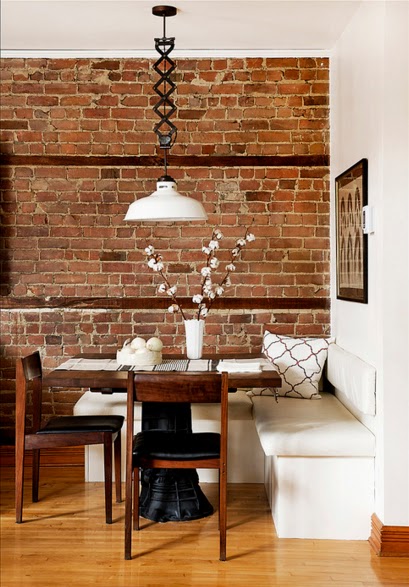 Białe siedziska w małej jadalni ze ścianą z czerwonej cegły