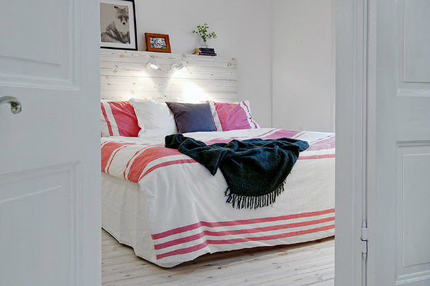 Dekoracja białego łóżka z dodatkami w rózowym i granatowym kolorze
