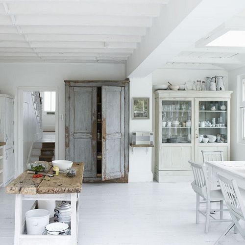 Biała konsola kuchenna z drewnianym blatem,szare drzwi w stylu schabby i biały tradycyjny kredens w kuchni