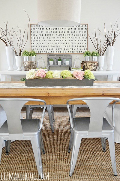 Szare krzesła Tplix, typografia na scianie ,drewniane skrzynki z kwiatami na stole w jadalni