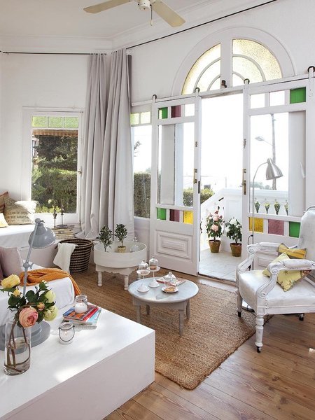 Stylowe białe drzwi z okragłym świetlikiem i kolorowymi szybkami,stylowe meble z recyklingu i dekoracje w stylu vintage w salonie