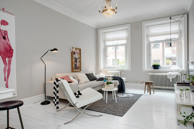 Kultowe pikowane białe fotele na metalowych nózkach,szary dywan i biała sofa w skandynawskim salonie